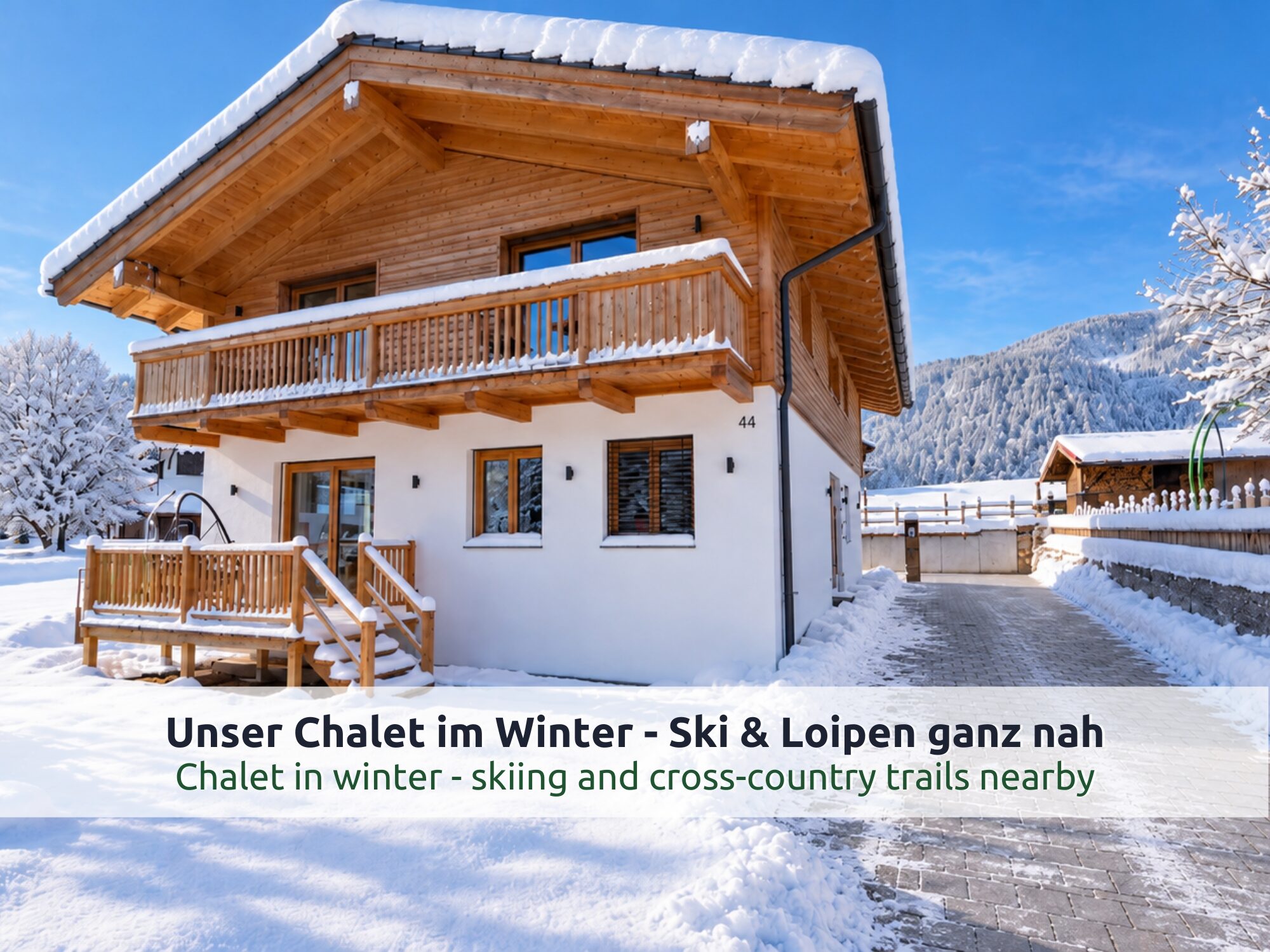 Chalet Reit im Winkl im Winter: Holzhaus mit Holzbalkon, Treppe zur Terrasse, verschneitem Garten und Bergen