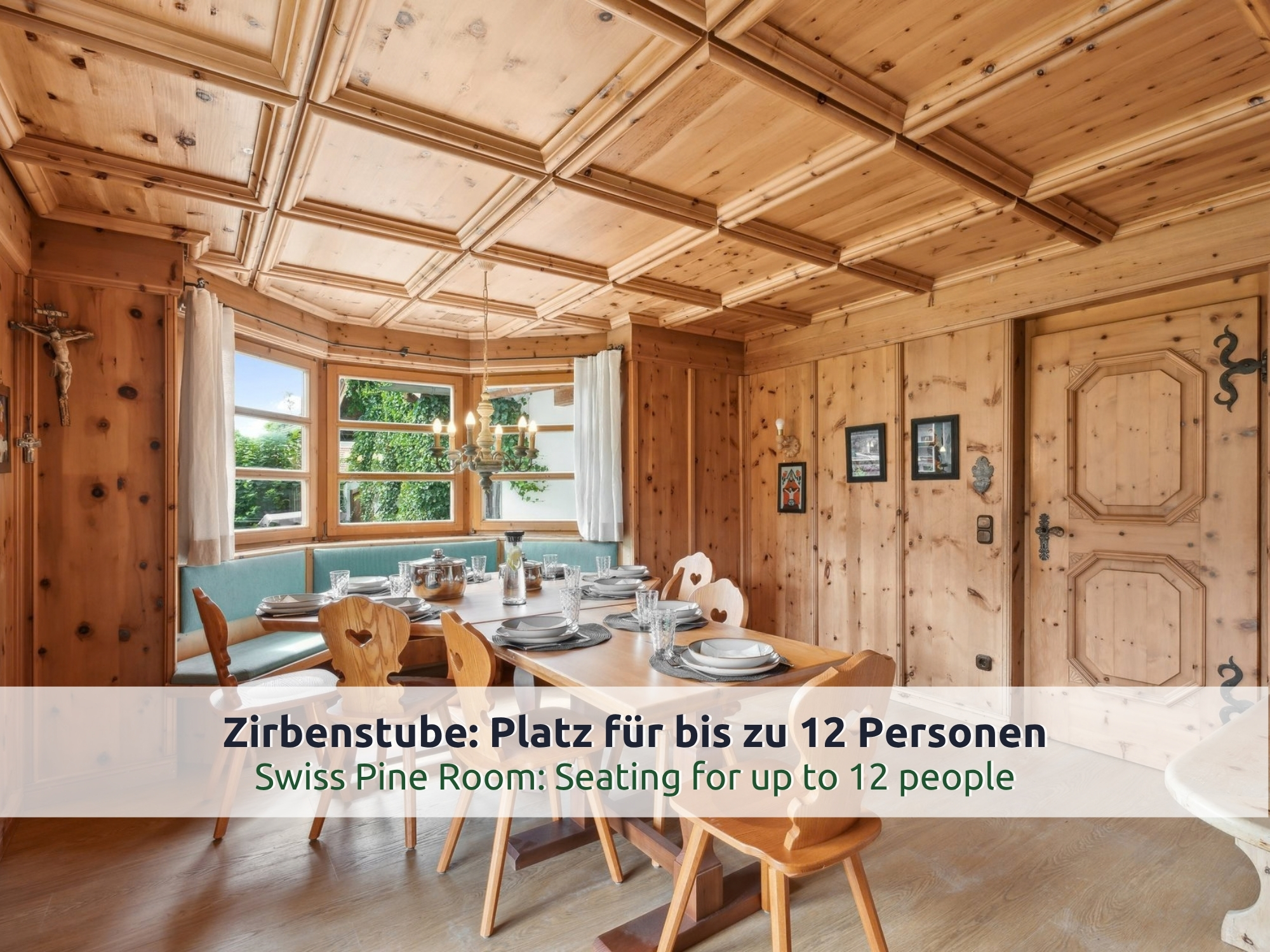 05 Villa Siegsdorf: Zirbenstube mit gedecktem Holztisch, Eckbank mit türkisen Polstern, Kassettendecke und Erkerfenster