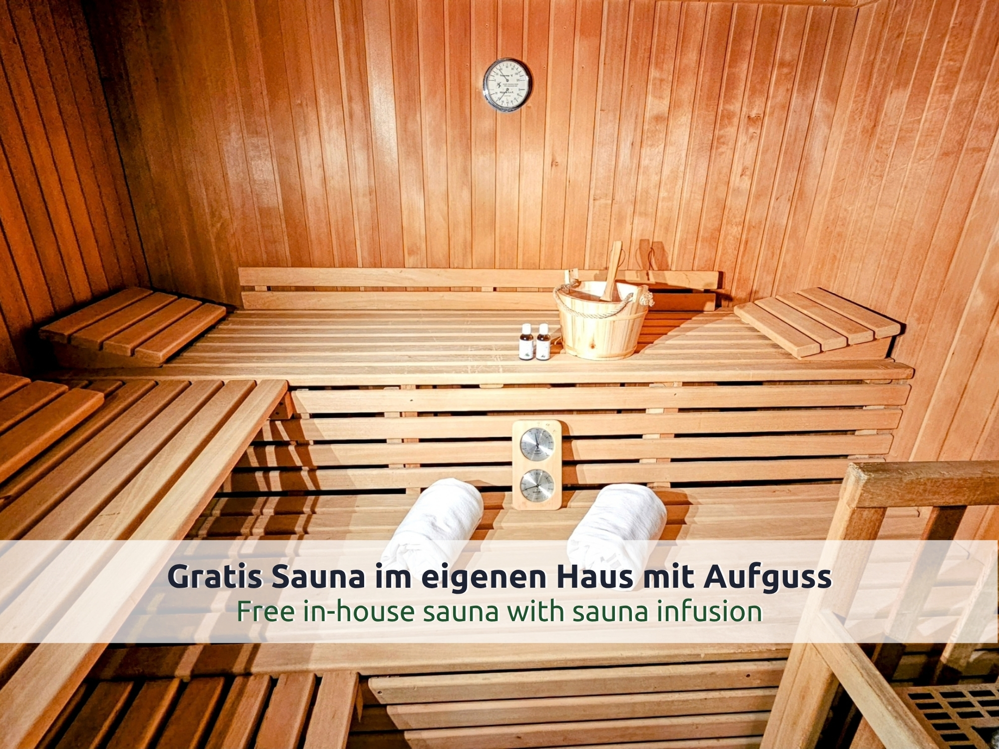 06 Villa Siegsdorf: private Sauna mit Bänken auf mehreren Ebenen, Aufgusseimer mit Kelle und gerollten Handtüchern