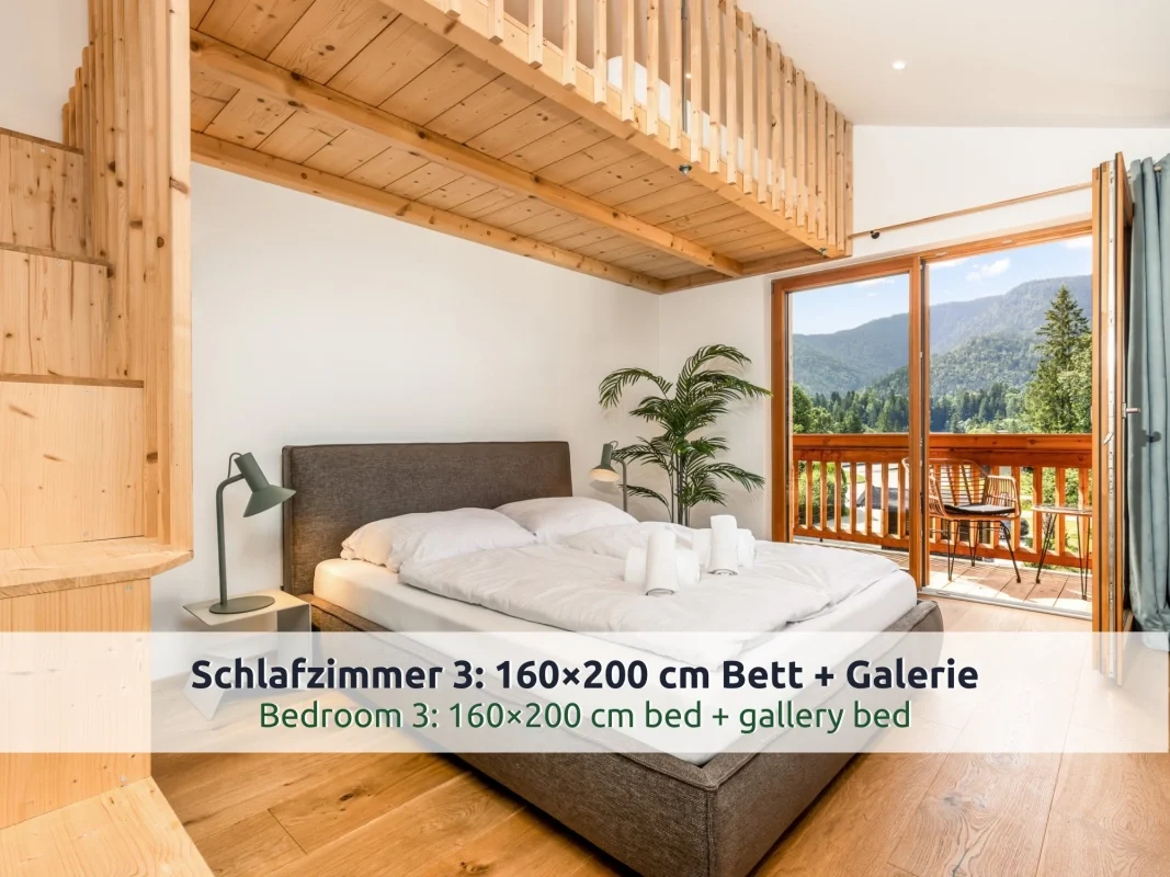 Chalet Reit im Winkl: Schlafzimmer mit Doppelbett, Galerie aus Holz und Balkontür mit Blick auf bewaldete Berge