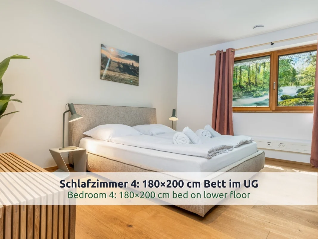 Chalet Reit im Winkl: Schlafzimmer im Souterrain mit Doppelbett, grauem Polster, Leselampen, Holzbank und Fenster mit Waldmotiv
