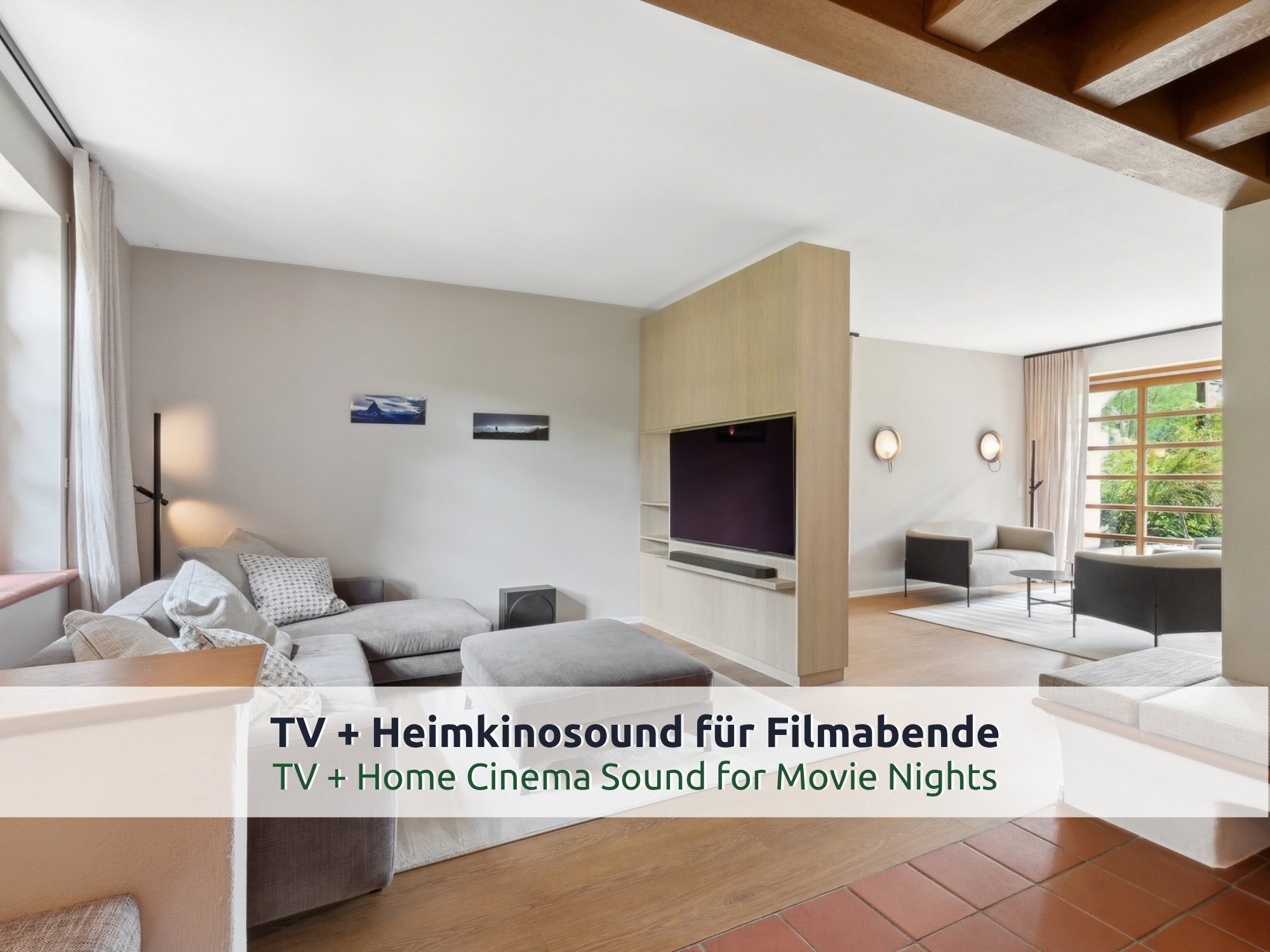 14 Villa Siegsdorf: TV-Bereich mit grauem Ecksofa, großem Fernseher mit Soundbar und Bergfotos an der Wand