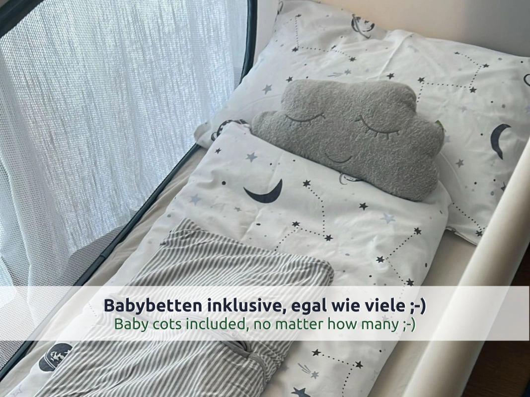 15 Ferienhaus Ruhpolding: Kinderreisebett mit Netzwand, bezogen mit Sternen- und Mondbettwäsche, Wolkenkissen und grau gestreiftem Schlafsack