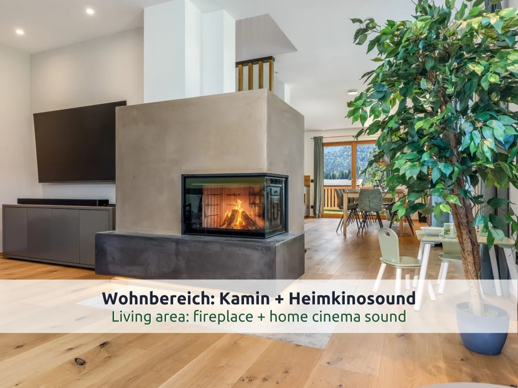 Chalet Reit im Winkl: offener Wohnbereich mit Kamin in Betonoptik, Fernseher und Kindertisch, im Hintergrund der Essbereich