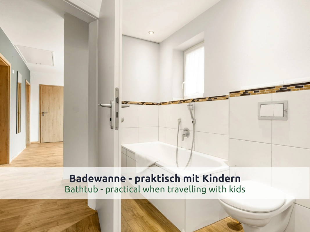 Ferienhaus Ruhpolding: Badezimmer mit Badewanne, WC und weißen Fliesen mit Mosaikbordüre