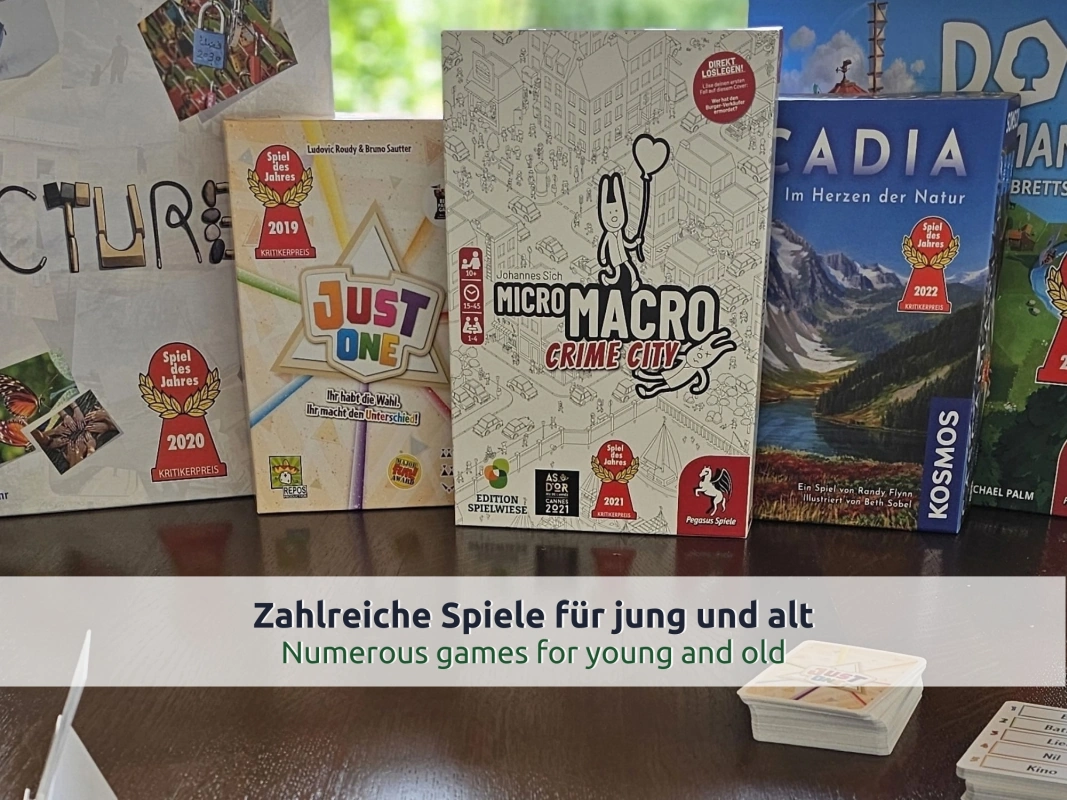 20 Ferienhaus Ruhpolding: mehrere Brettspielschachteln und Kartenspiele auf einem dunklen Holztisch