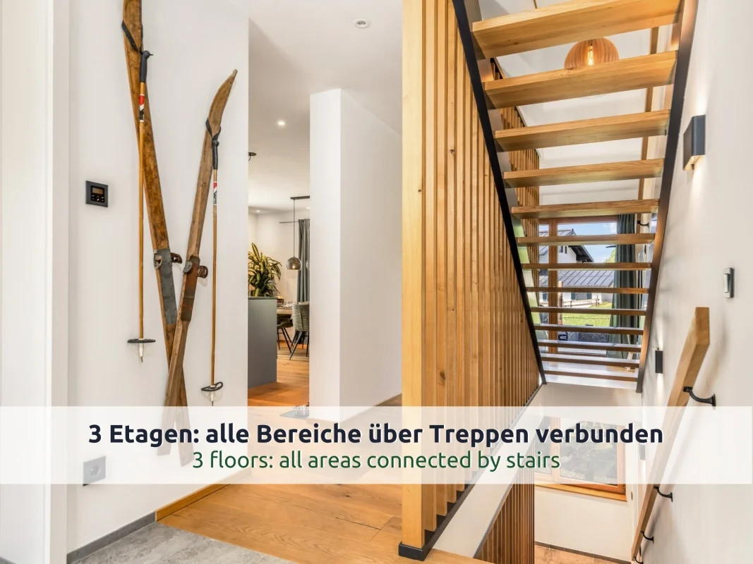 Chalet Reit im Winkl: Flur mit alten Holzskiern als Wanddeko, Treppe nach oben und unten mit Lattenwand und Blick in Küche und Essbereich