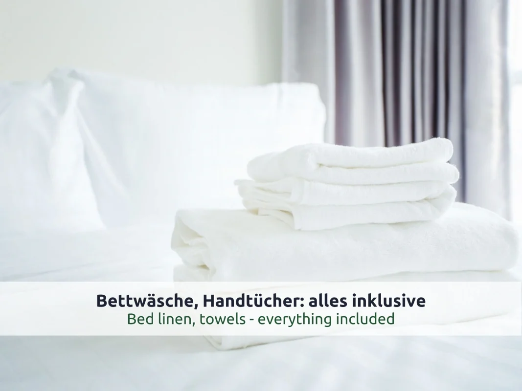 Chalet Reit im Winkl: gefaltete weiße Handtücher auf einem frisch bezogenen Bett, im Hintergrund ein Vorhang
