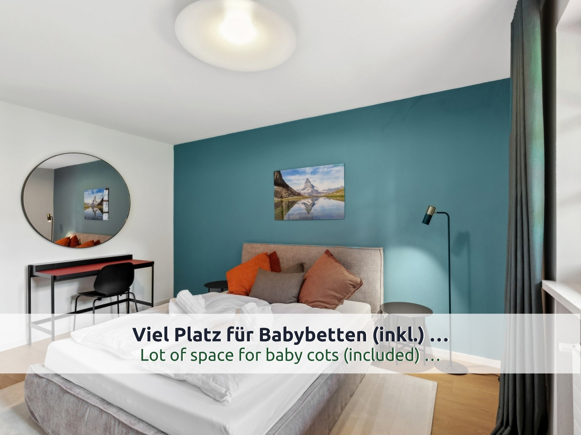 32 Villa Siegsdorf: Doppelbett mit weißer Bettwäsche und gerollten Handtüchern, roter Schreibtisch und Bergbild an petrolfarbener Wand