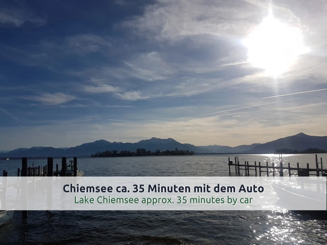 Ausflugsziel Chiemsee: Holzstege, Boote und eine Insel im Gegenlicht vor den Bergen