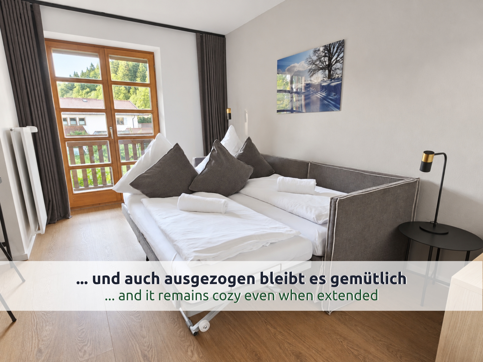 39 Villa Siegsdorf: ausgezogenes graues Bettsofa mit zwei Schlafplätzen, weißer Bettwäsche und gerollten Handtüchern