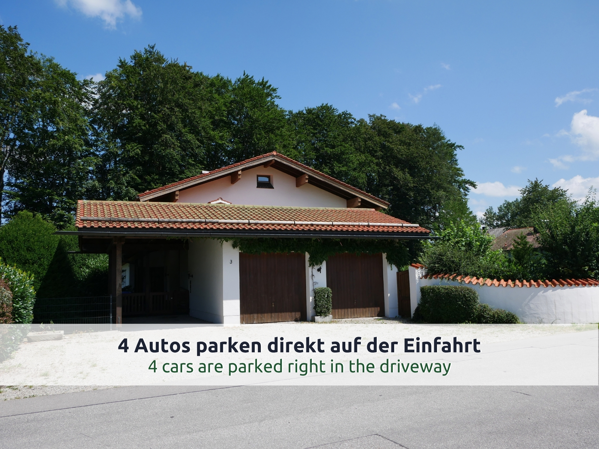 53 Villa Siegsdorf: Nebengebäude mit zwei Garagentoren und Carport, Kiesfläche zum Parken, Bäume und eine weiße Mauer